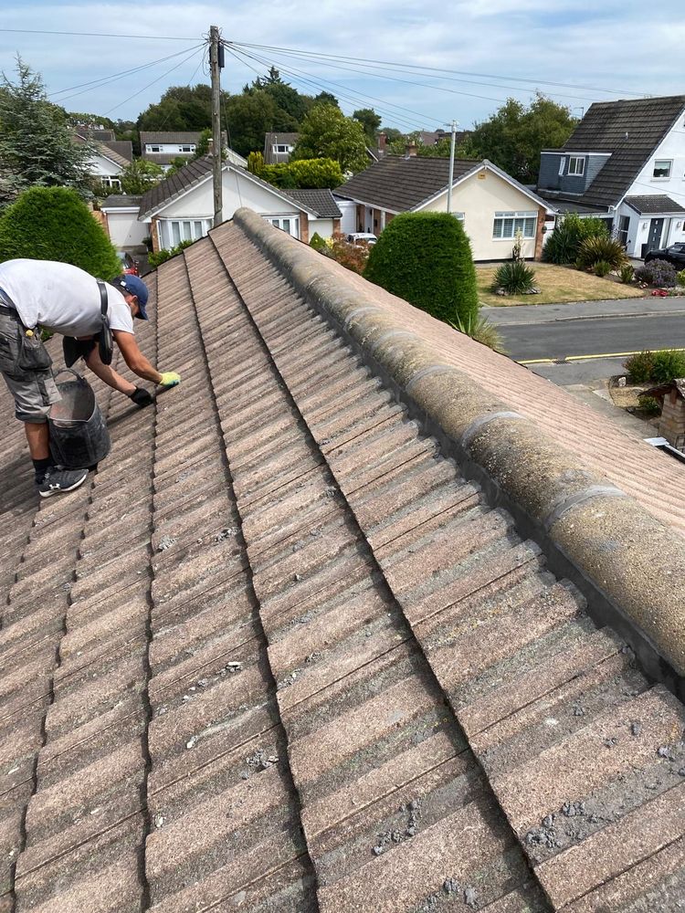 Roofer closely inspecting ridge tiles during a professional roof survey, Merseyside