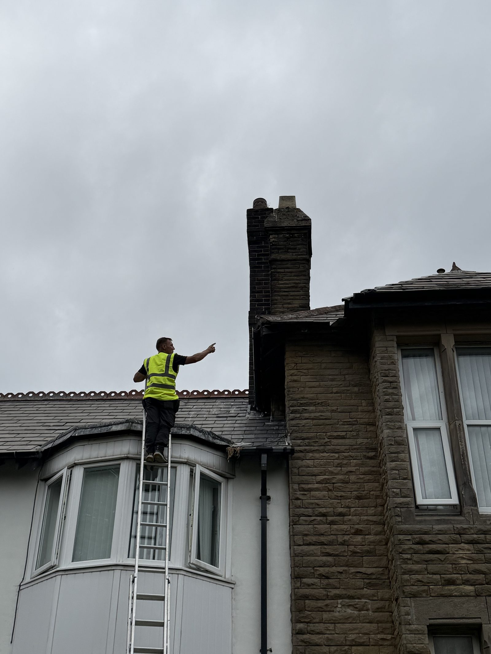 Roofer inspecting guttering and roofline on a Merseyside property